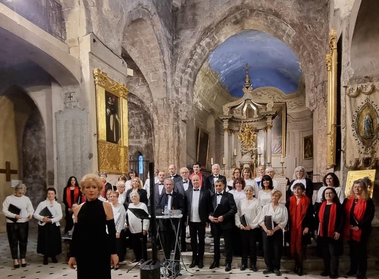 Concert choral au Centre de Lutte contre le Cancer - Antoine Lacassagne à Nice, avec des chanteurs en costume devant un autel décoré.